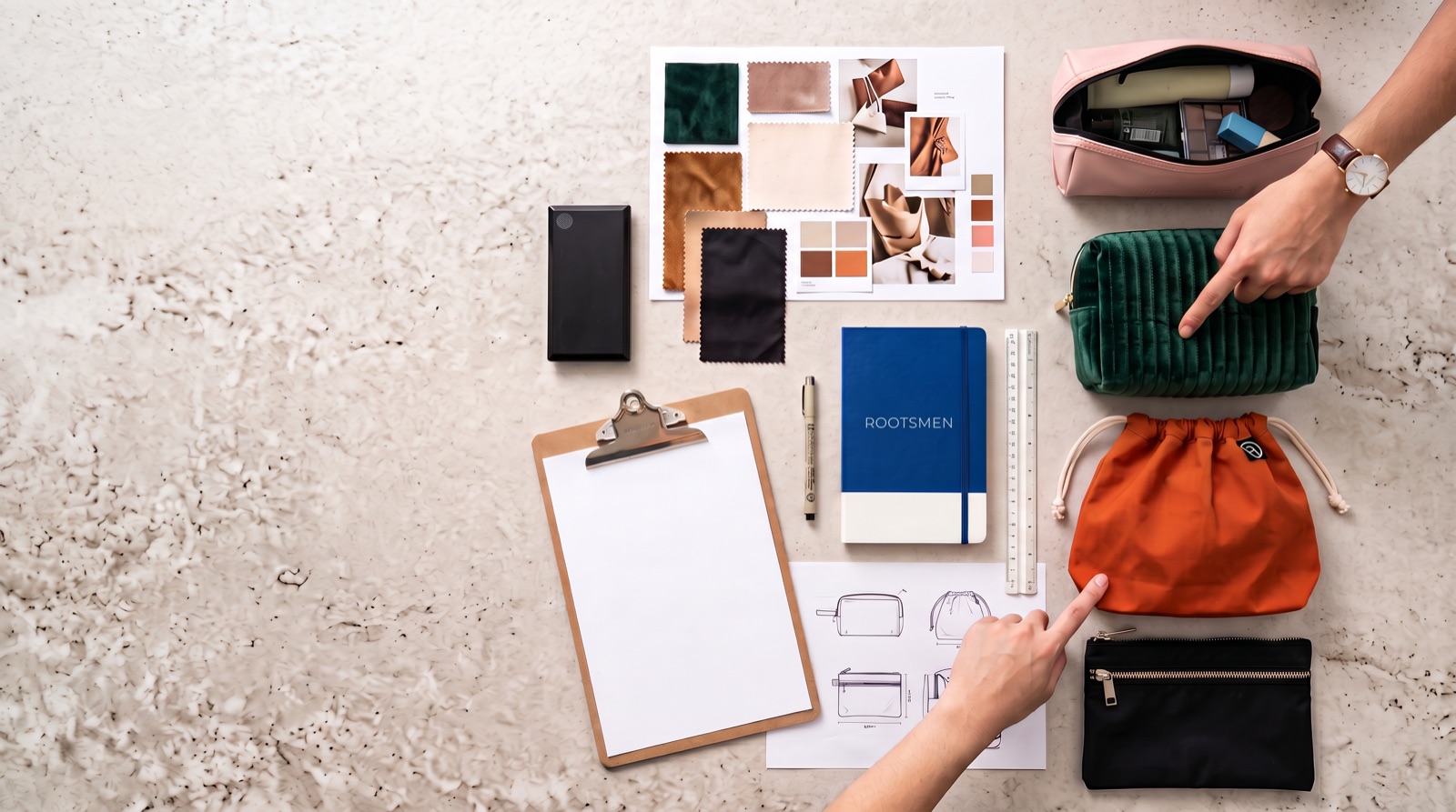 Pattern pieces, fabric swatches and a prototype cosmetic bag laid out on a development table
